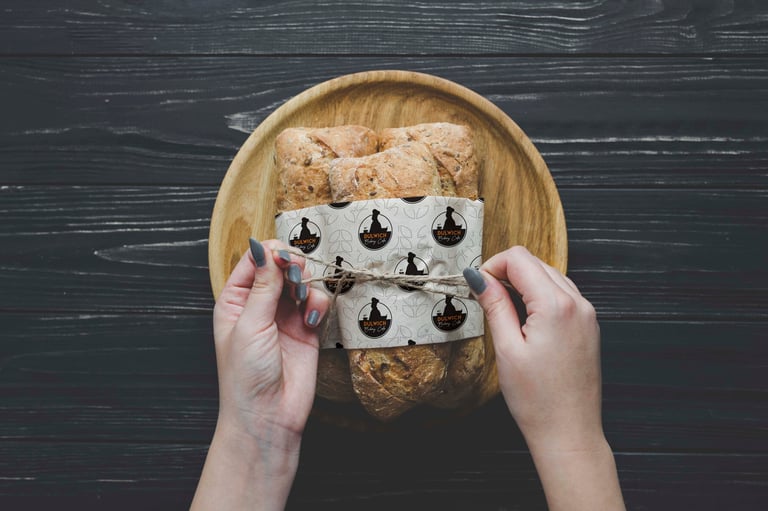 Hands holding an open carton of eggs with egg illustrations printed on the carton, placed on a rustic wooden plate against dark wood background